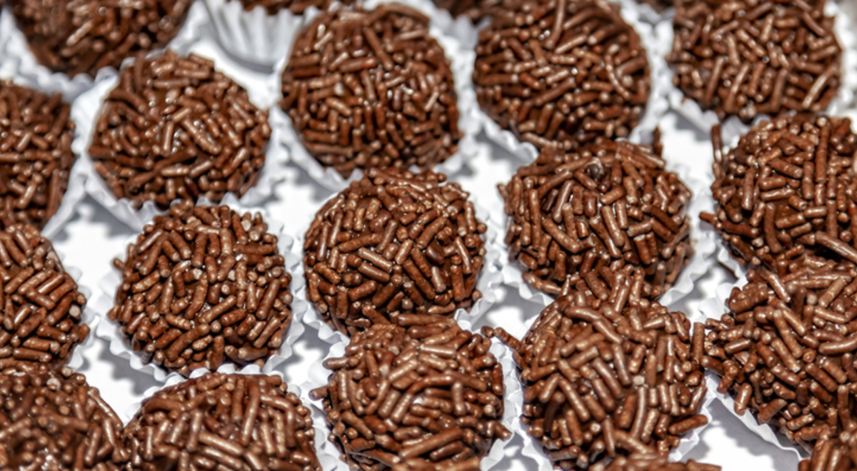 Seen from above, on a white tray, packed in white paper forms are some chocolate sweets called brigadeiro in Brazil.