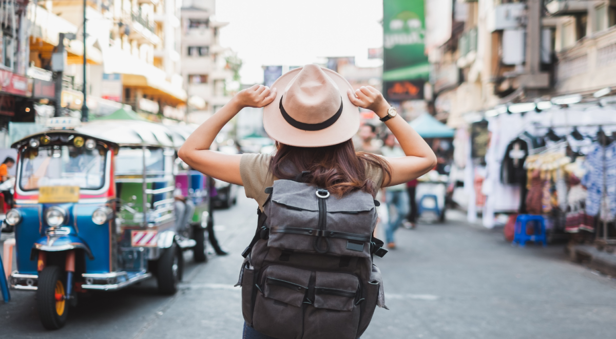 person with backpack and hat standing near a Tuk Tuk in khaosan road Bangkok 