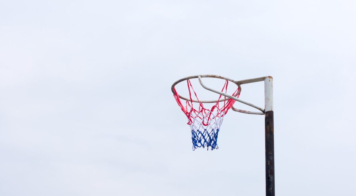 A netball hoop against a grey sky.