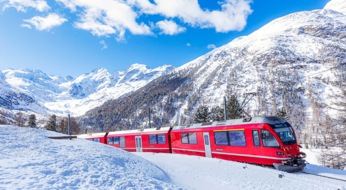 Red train travelling through the snowy landscape of Switzerland
