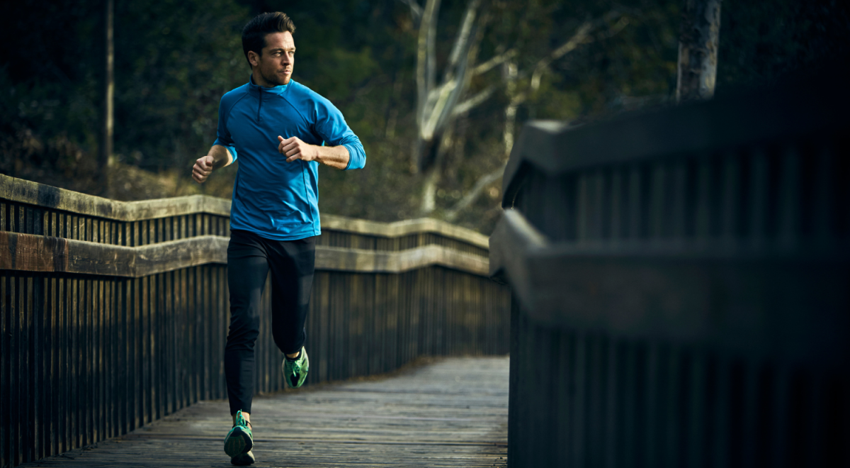 a guy in blue longsleeves shirt and black jogging pants running through a narrow bridge