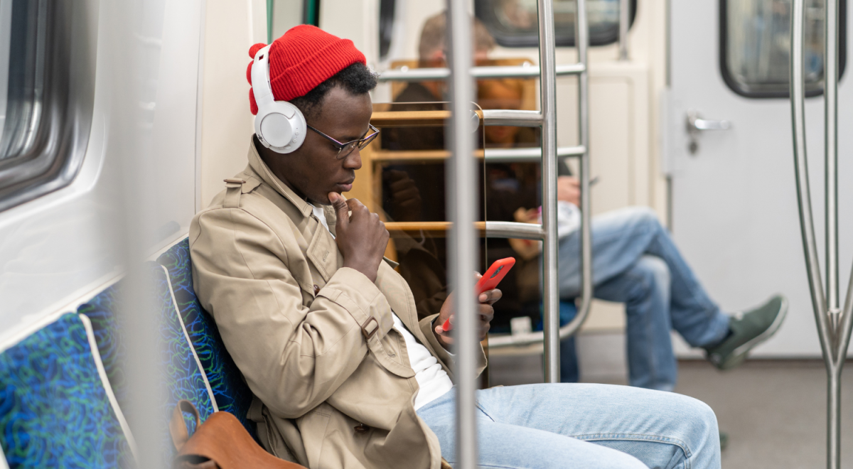 Man on a train listening to music using wireless headphones