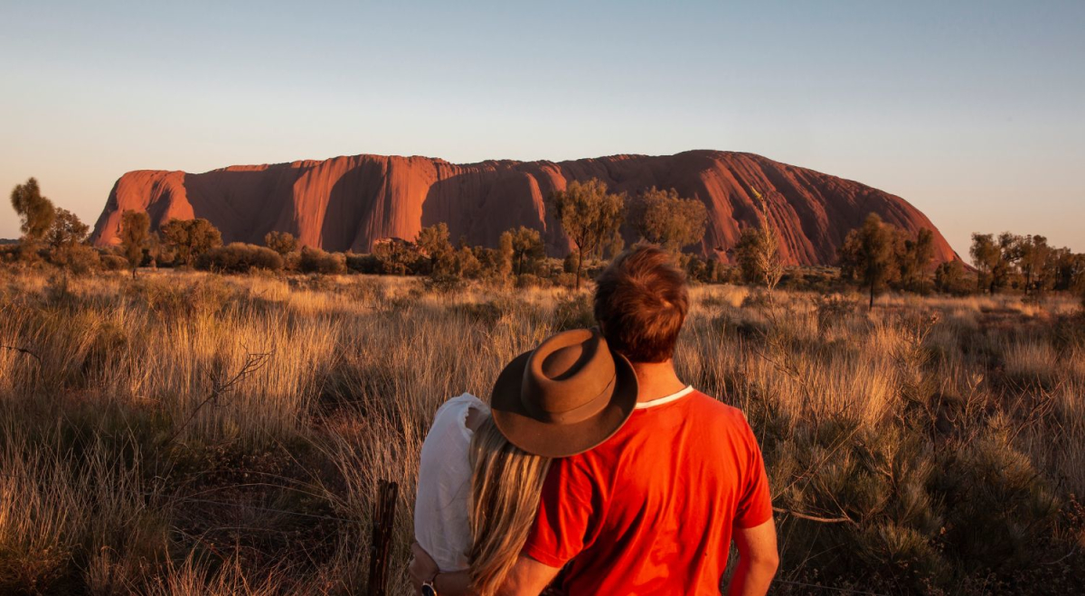 Two young people standing and looking at Uluru