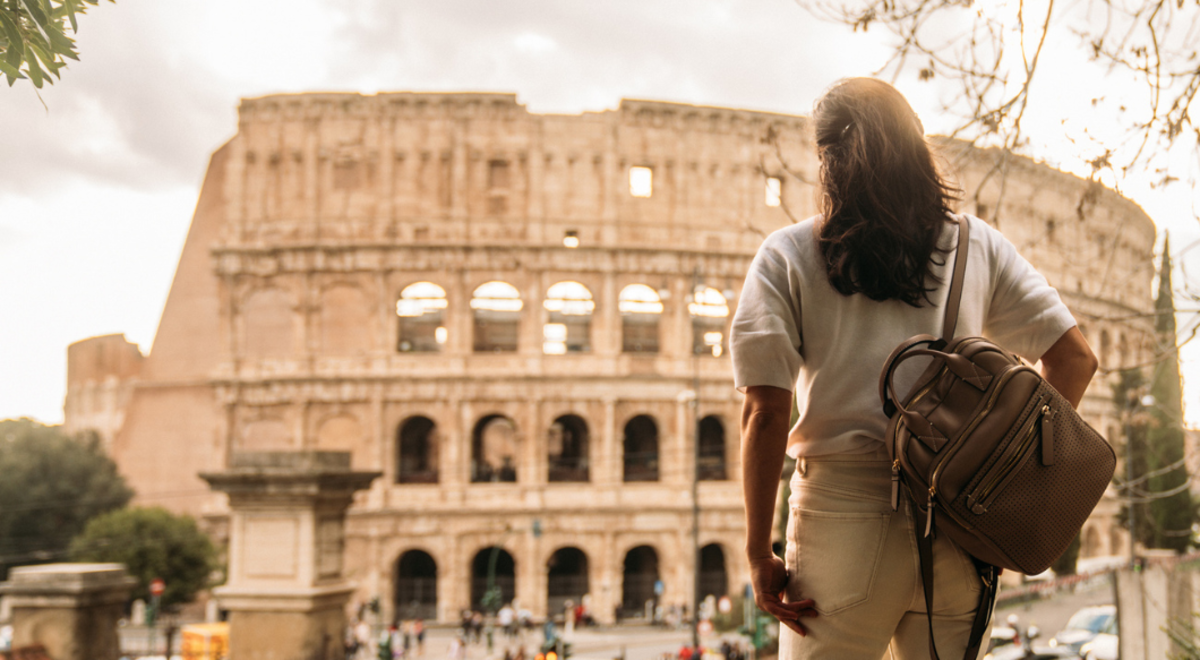 Lady with backpack facing the Colosseum in Italy