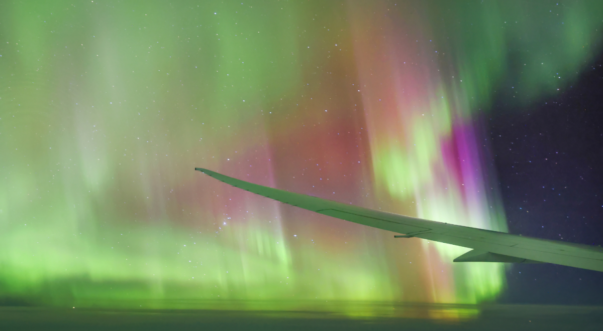 Plane wing flying through Aurora Australis 