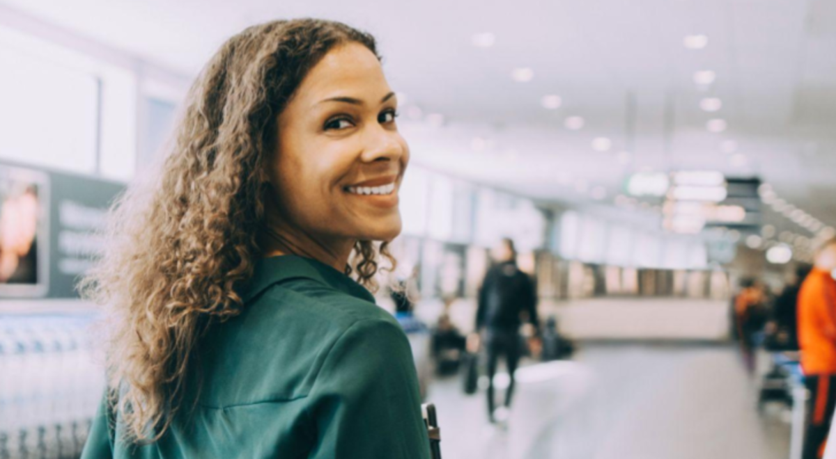 Woman walking through an airport looking back at the camera