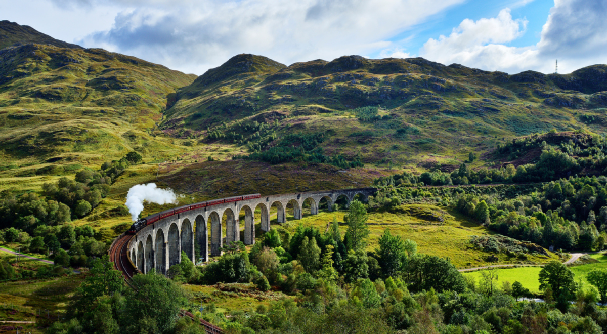 train running over bridge in mountains of scotland