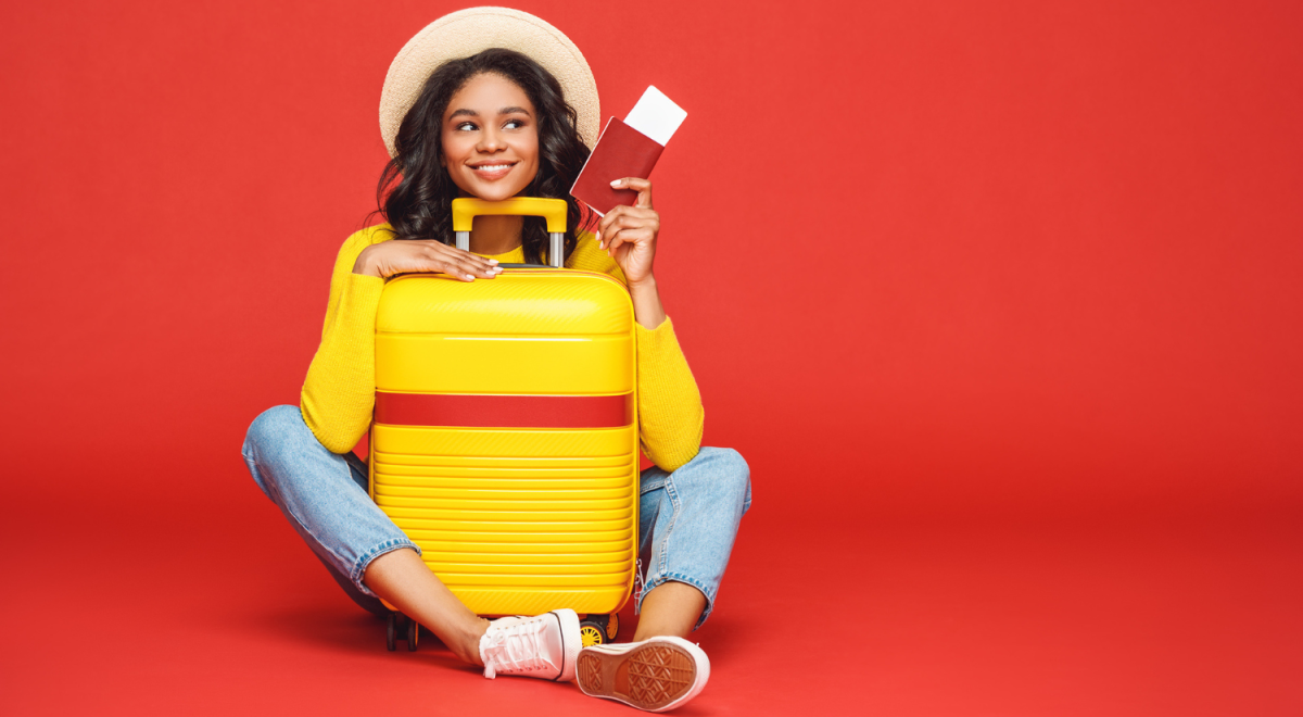 lady sitting on ground with legs around suitcase and holding ticket on red background