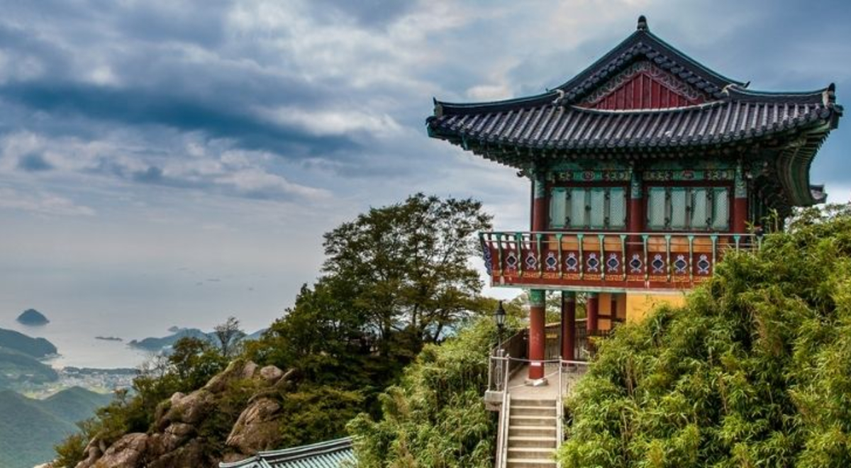 Temple on top of cliff in south Korea with Mountains and sky in background. 