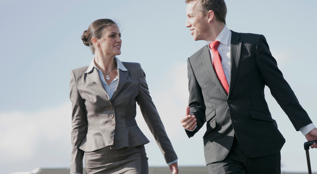 A professionaly dressed man and woman walking together off the tarmac