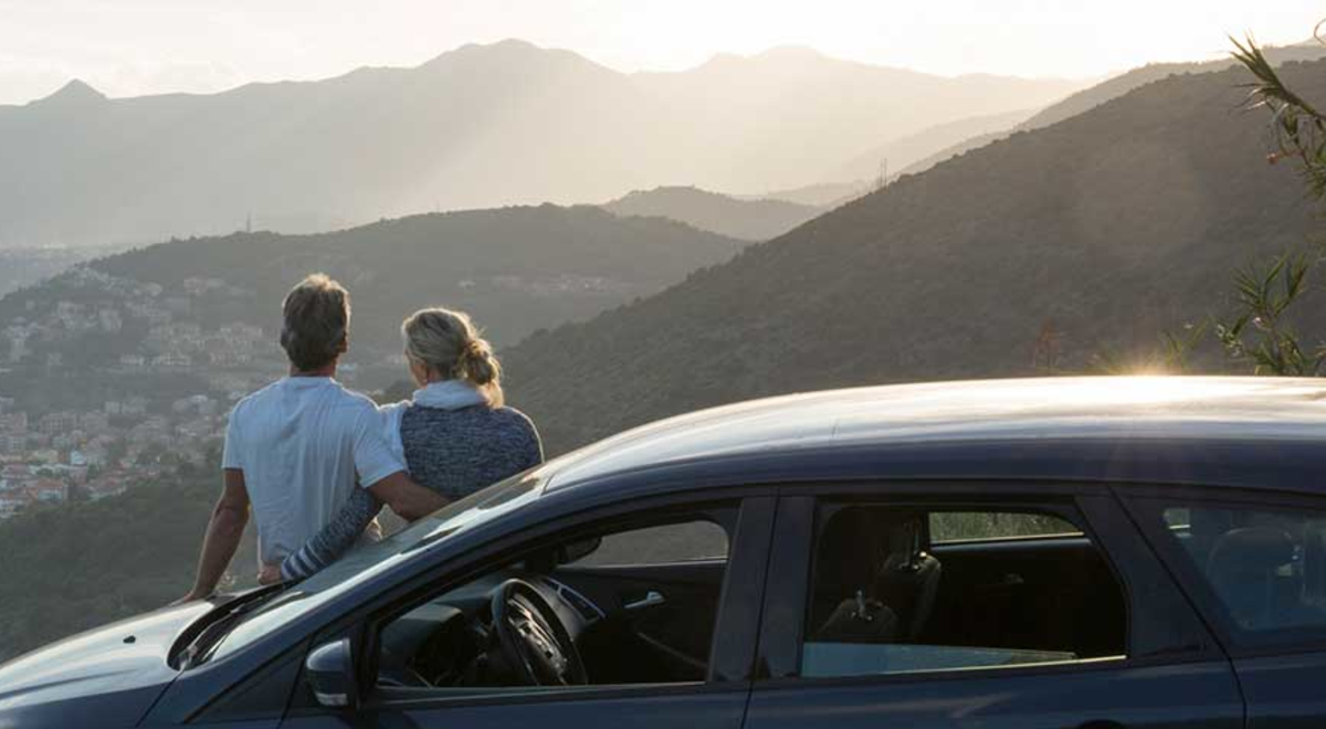 Middle aged couple leaning on a car admiring the view 