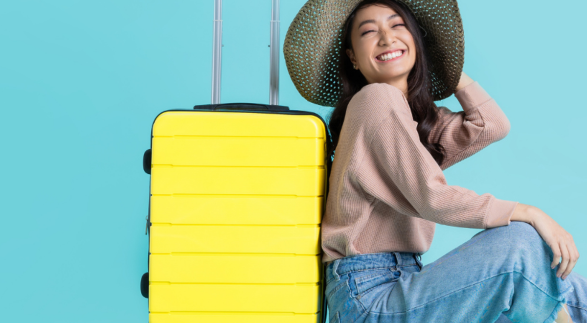Woman leaning against her yellow suitcase 