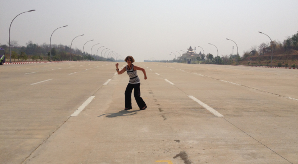 a short-haired woman dancing in the middle of the airport's highway