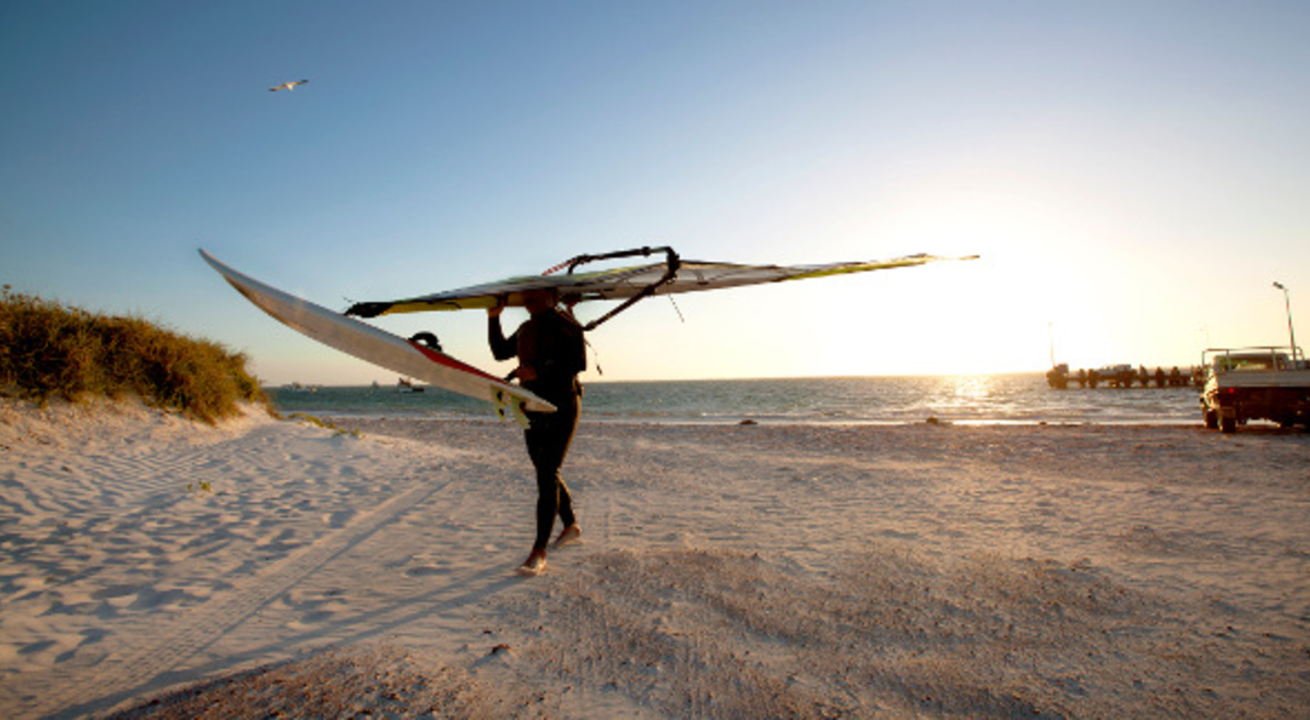 Person holding a wind surf on the beach at Lancelin