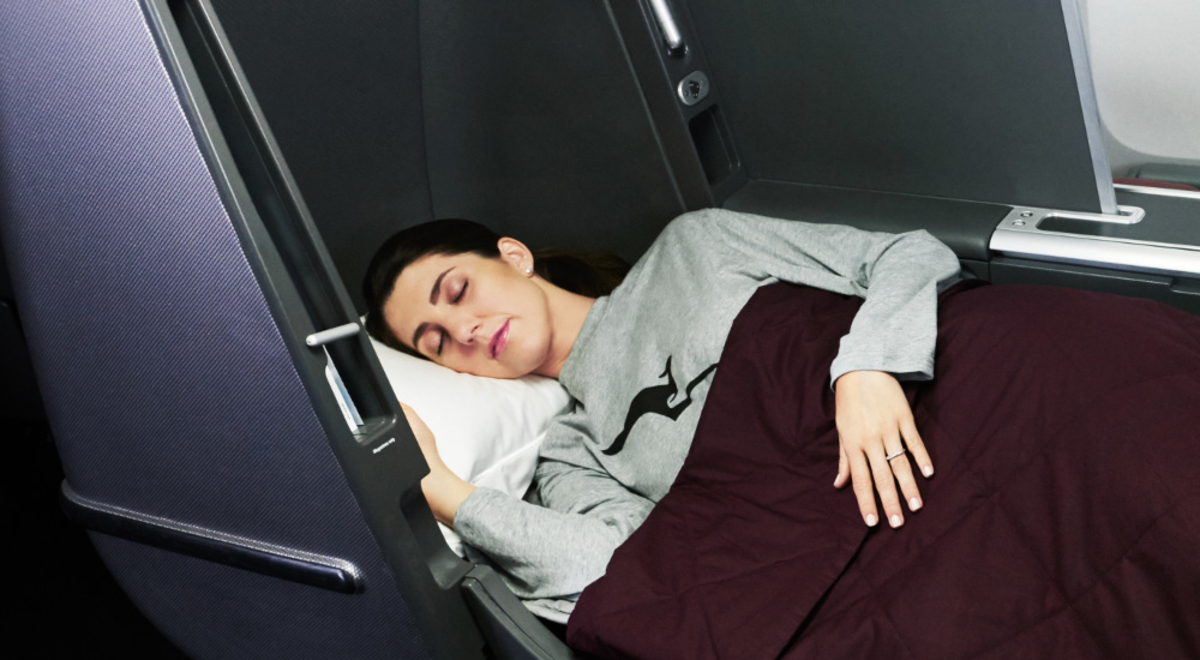 A woman sleeping on her Qantas Business Class lay flat seat