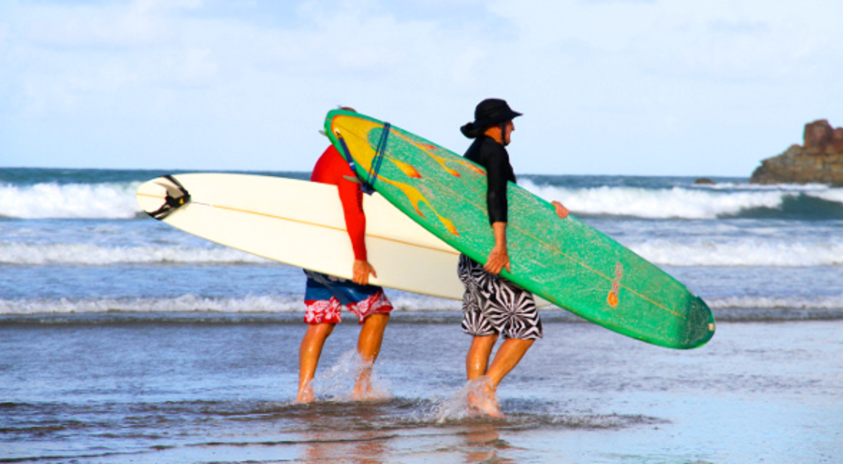 Two men walking on the beach with their surfboards