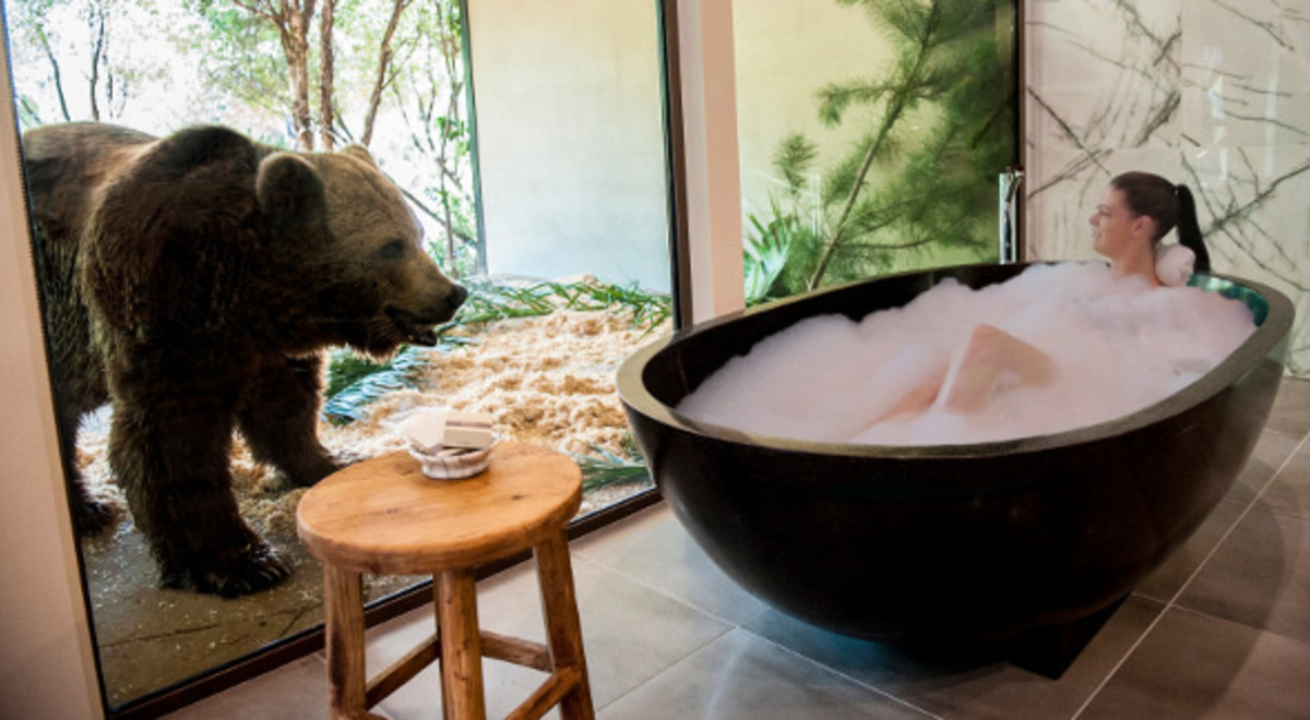 Lady enjoying a bubble bath while a bear approaches