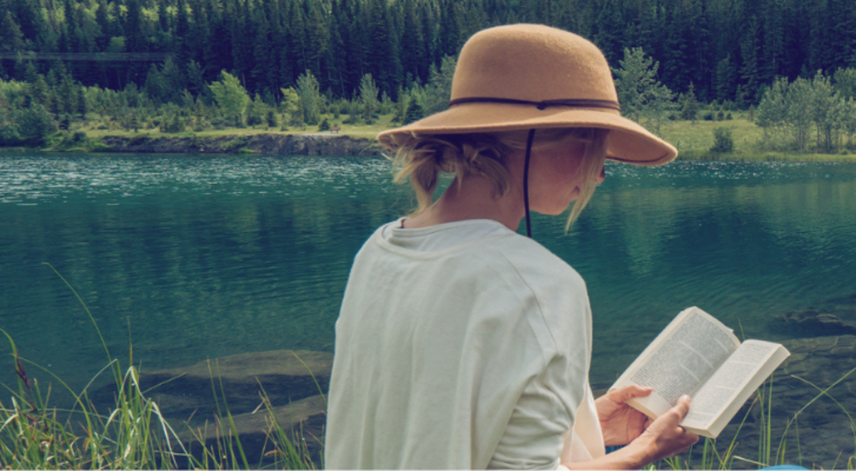 Lady reading a book beside the river