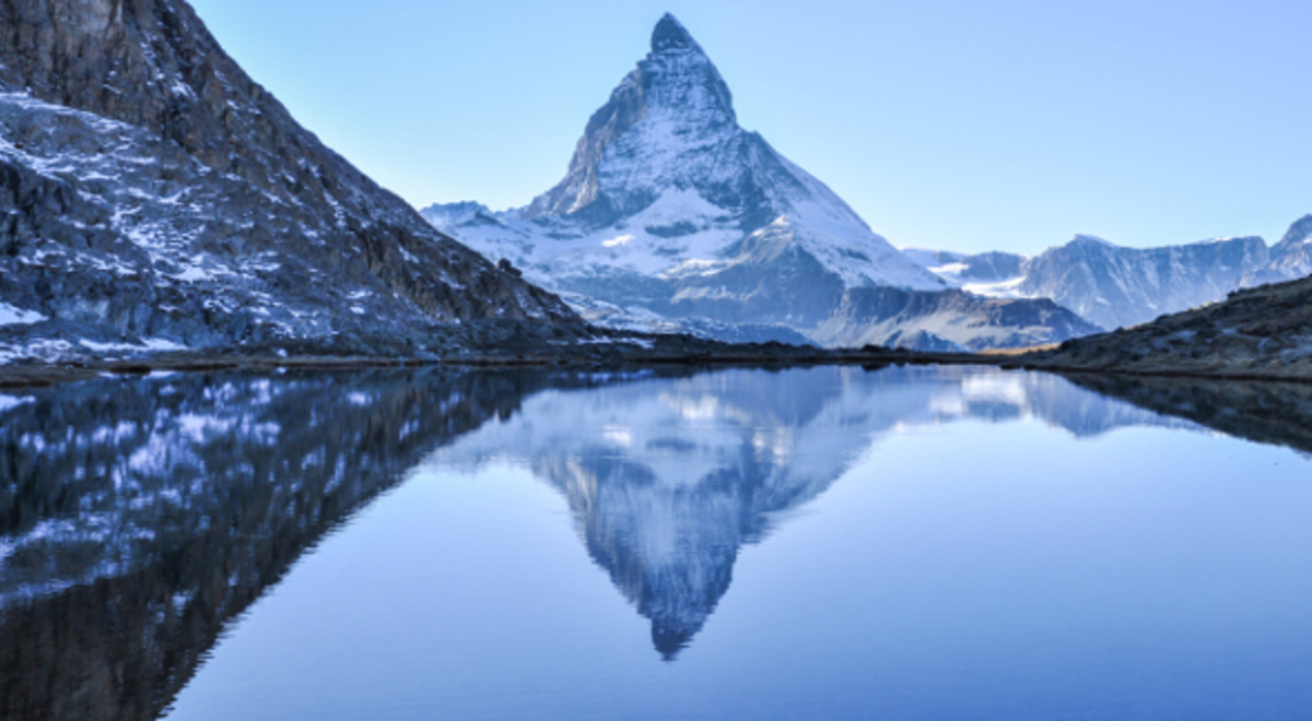  The image of the snowy pointy mountain is reflected on the water