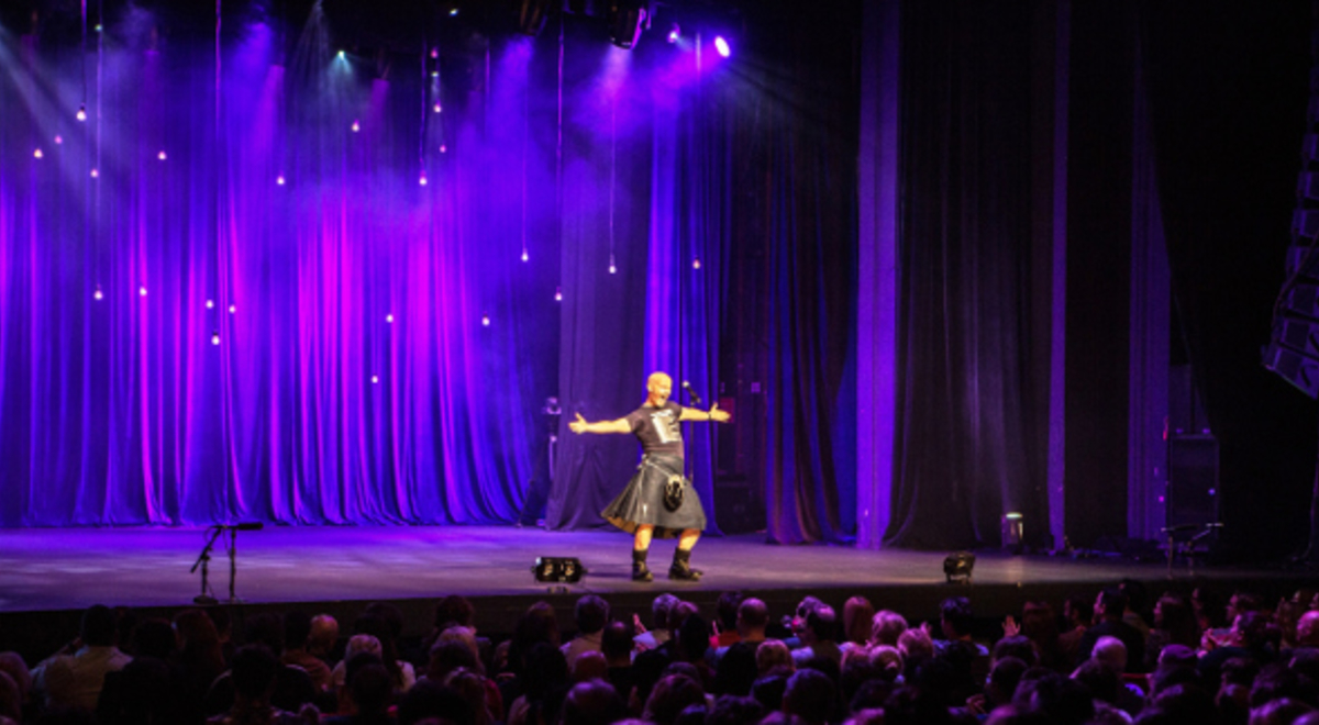 Stand up comedy in front of viewers with purple curtains as background