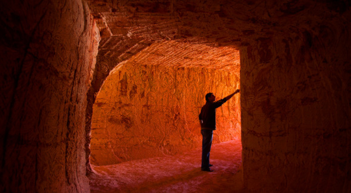 a man wandering along the tunnel and touching its walls