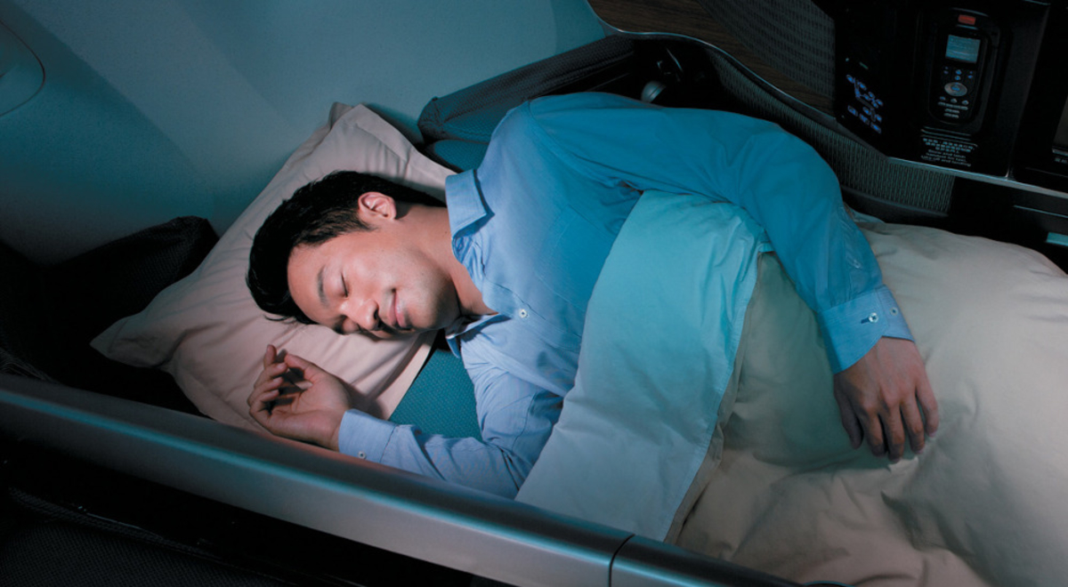 A man sleeping in his business class seat on Cathay Pacific