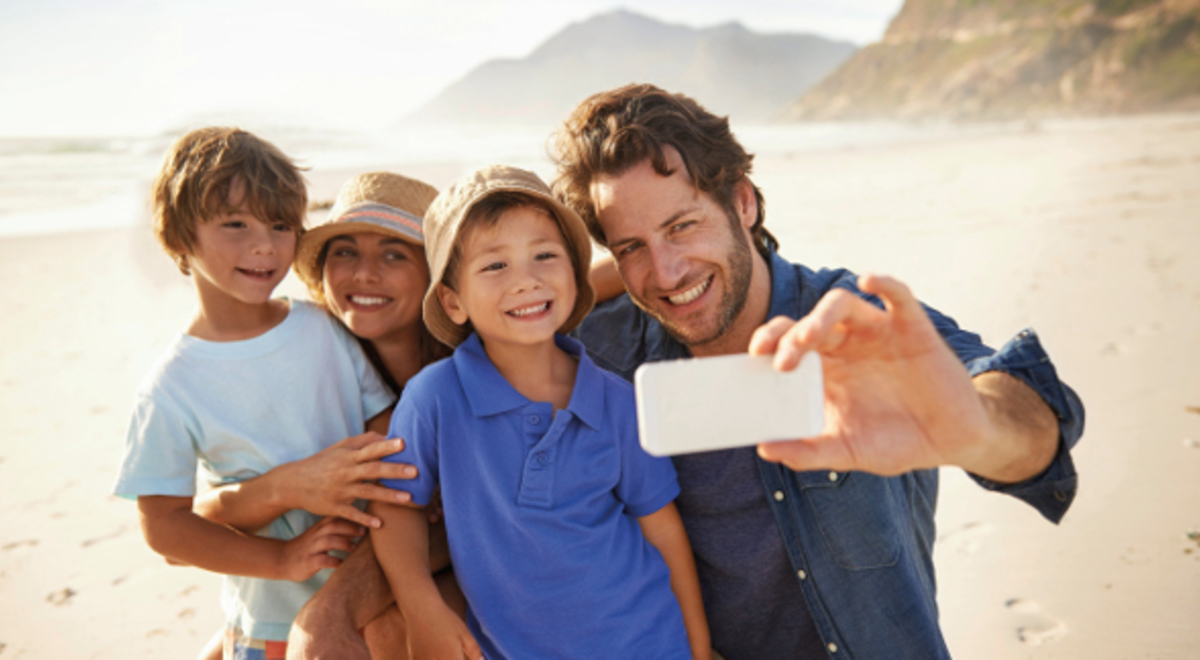 A family of four taking selfie at the beach