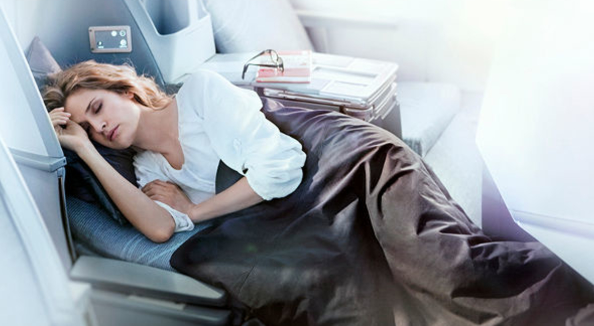 a redhead girl sleeping comfortably in Finnair's business class with a book and glasses on her side