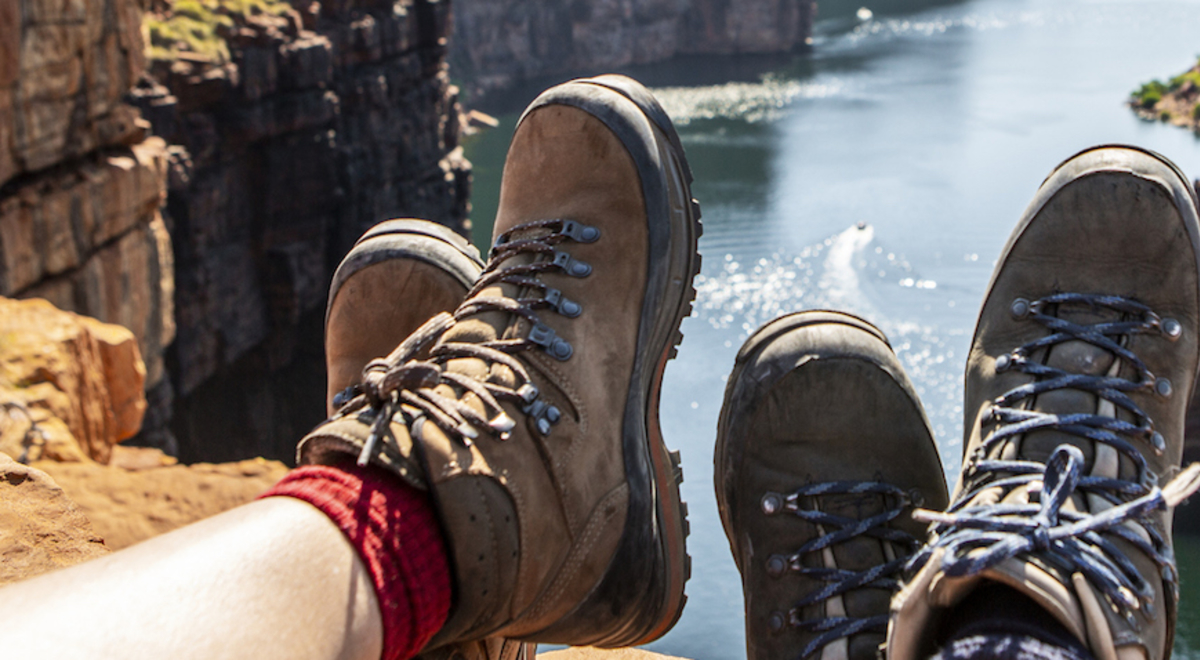 friends showing their tactical boots while sitting on the top of their hike