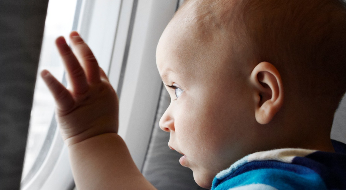 a baby staring curiously outside the airplane's window