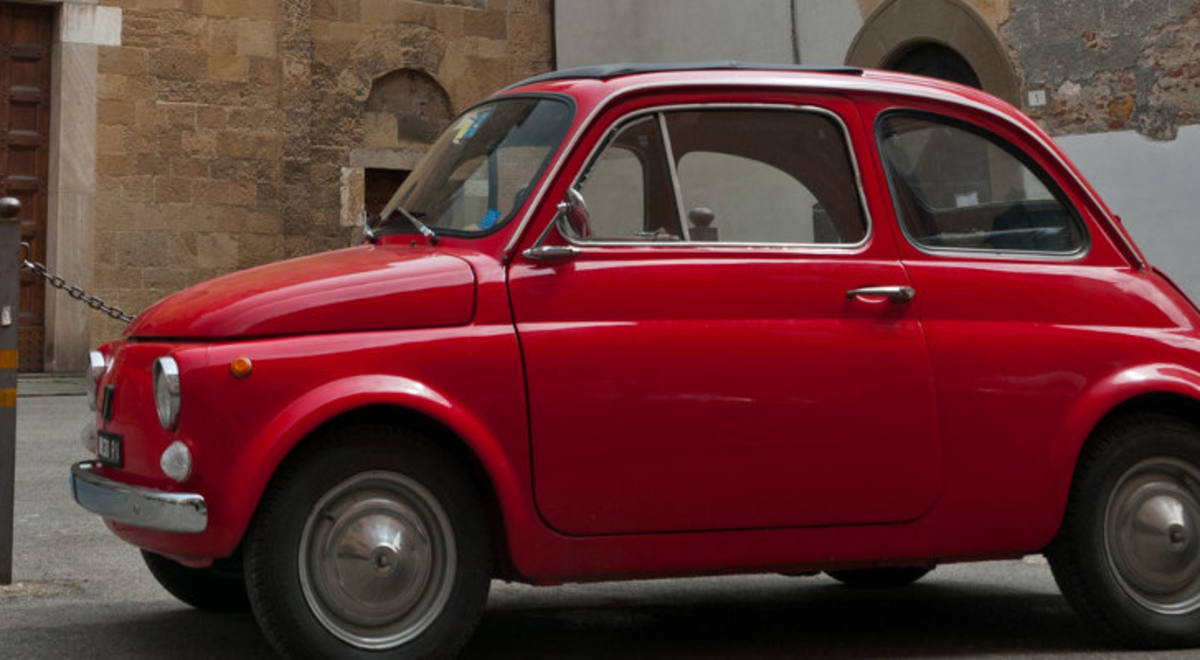 A clean, small, red car parked on an old street