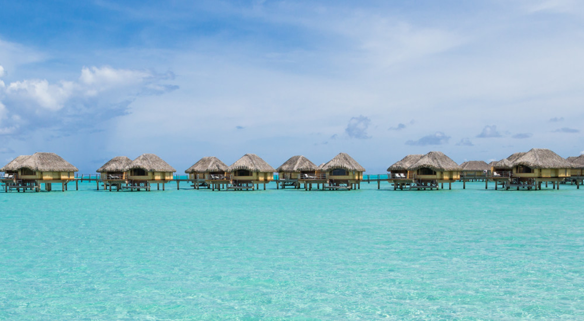 A distant shot of luxury overwater bungalows over the blue waters of Bora Bora