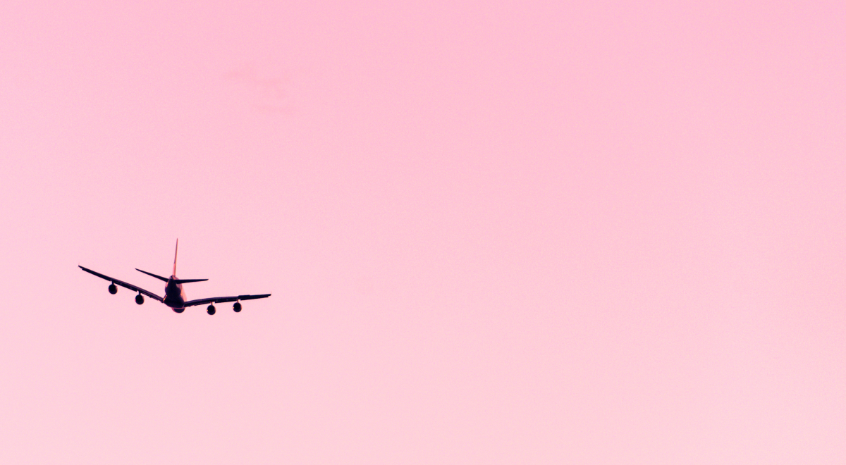 Airplane soaring through the pink skies
