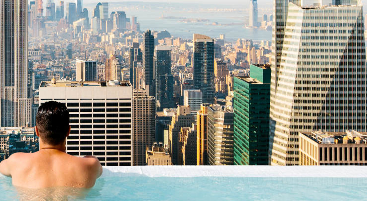 Man lounging on the edge of an infinity pool on top of a building
