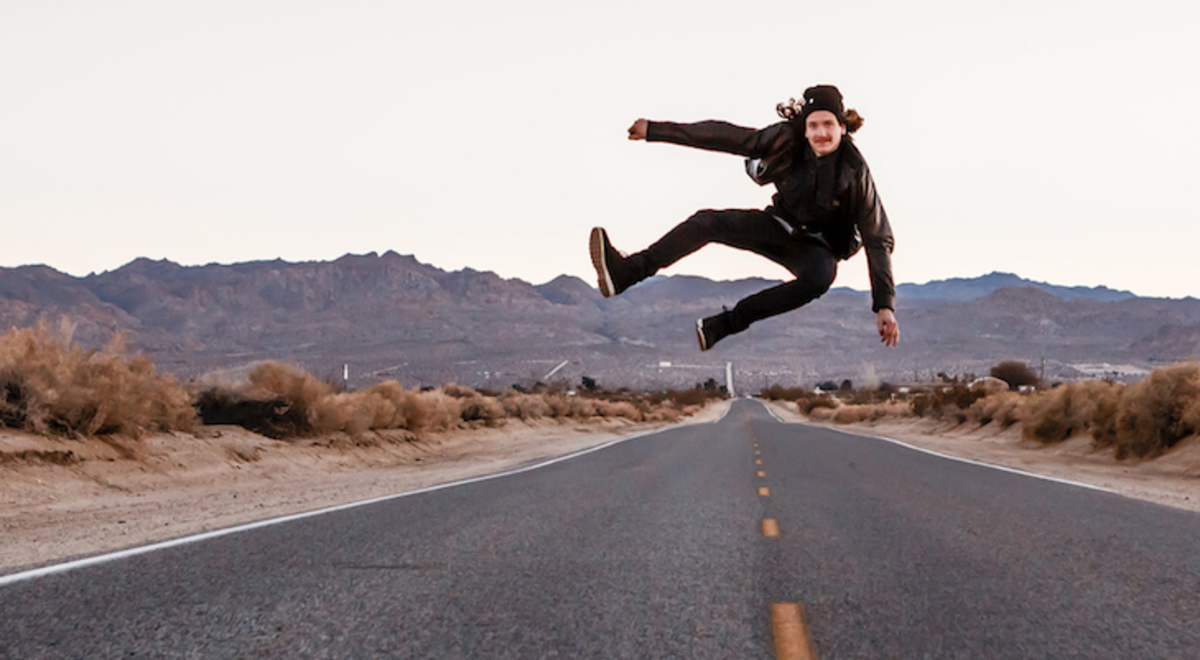 Person doing a jump shot in the middle of a deserted road