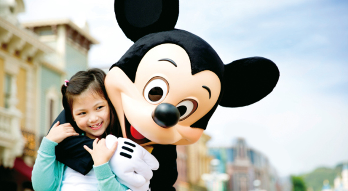 Mickey mouse hugging a young tourist