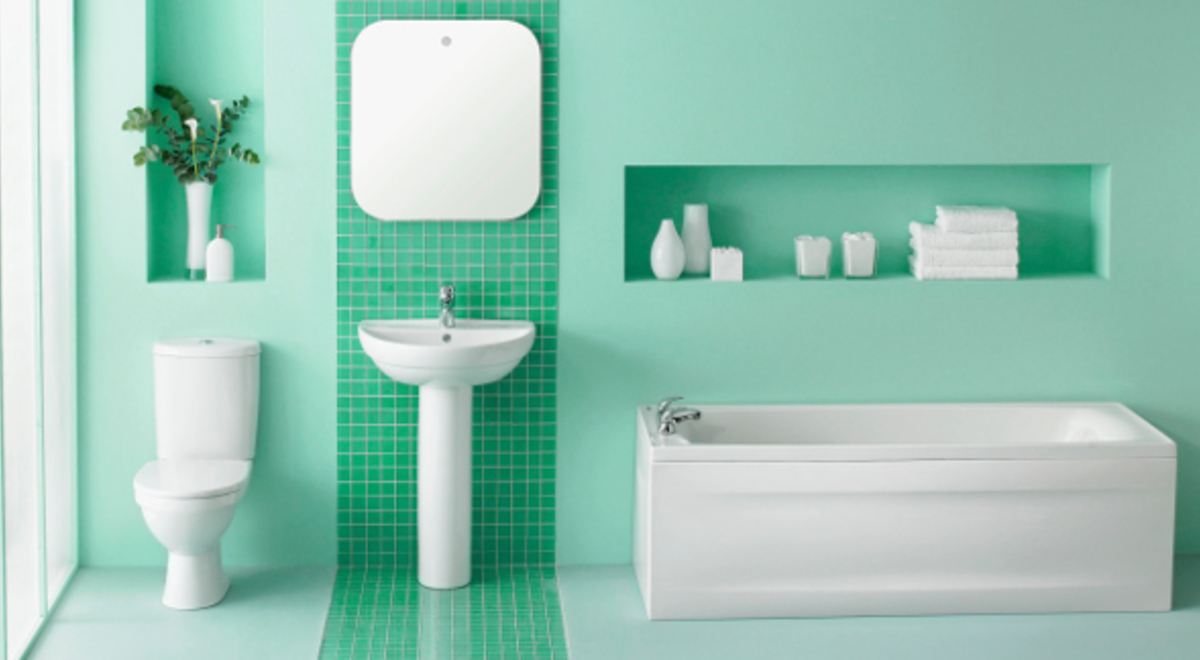 a restroom with white furniture and accessories and green tiles