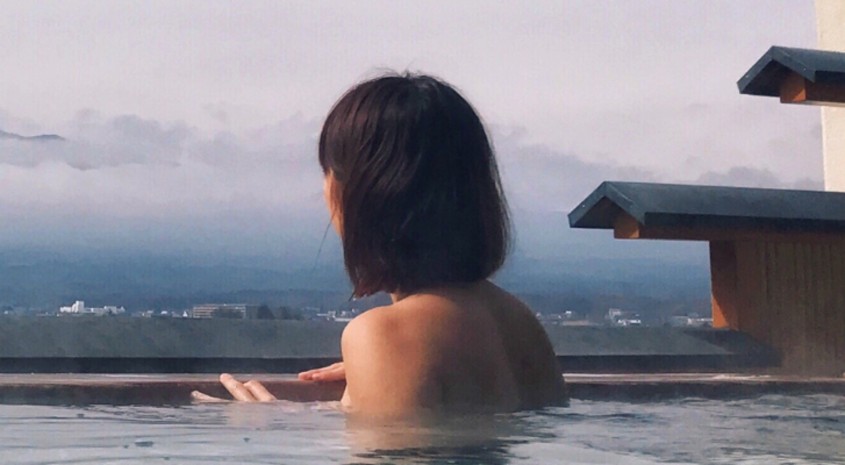 Woman swimming in spa looking out to mountain view 