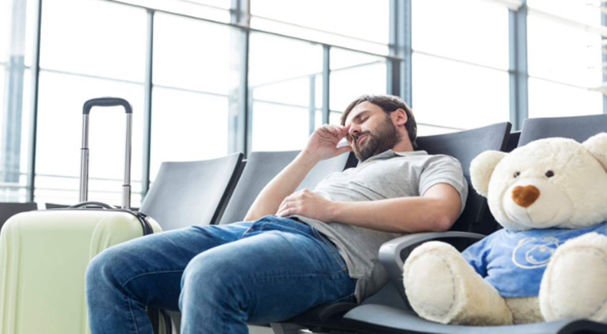 Man with his Teddy bear napping while waiting for his flight 