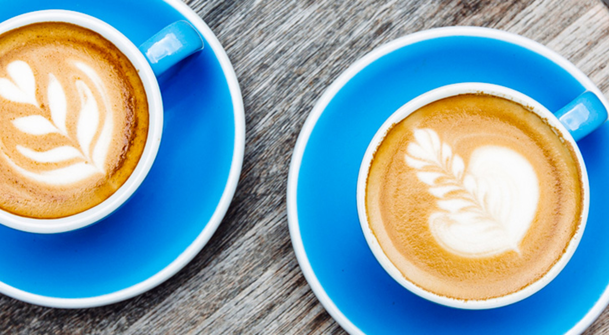 two blue cups of coffee with leaves latte art