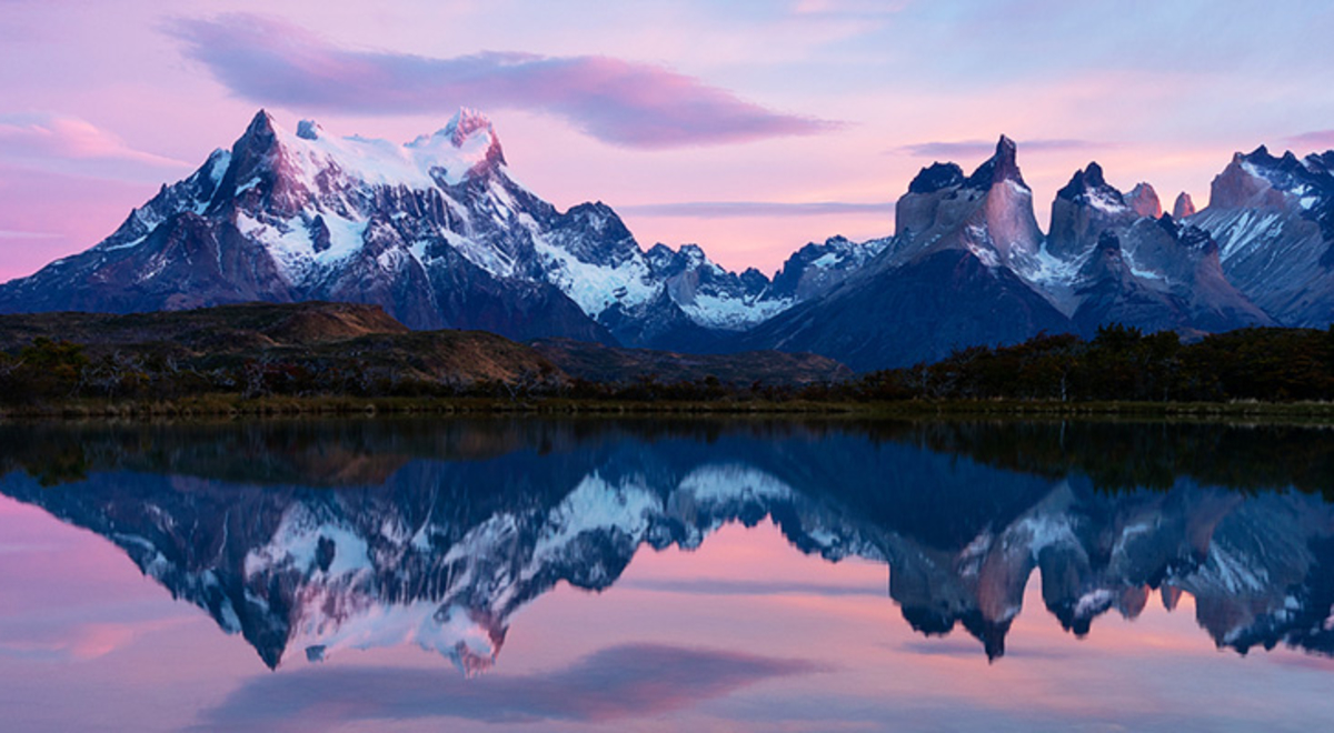 torres del paine mountain's image is reflected on the water while the sky on the background is a mix of purples, pinks, and blues