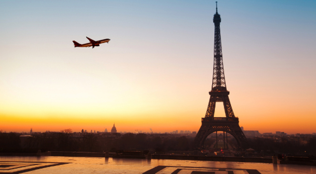 A plane flying past the Eiffel Tower in Paris at sunset