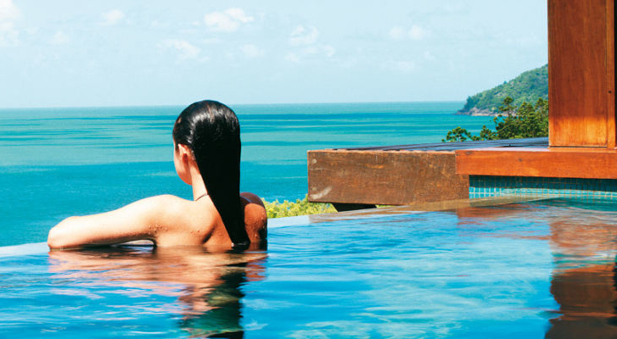 Woman in pool looking towards the ocean 