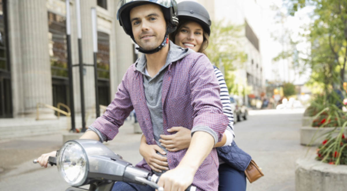Man and woman riding on a scooter together 