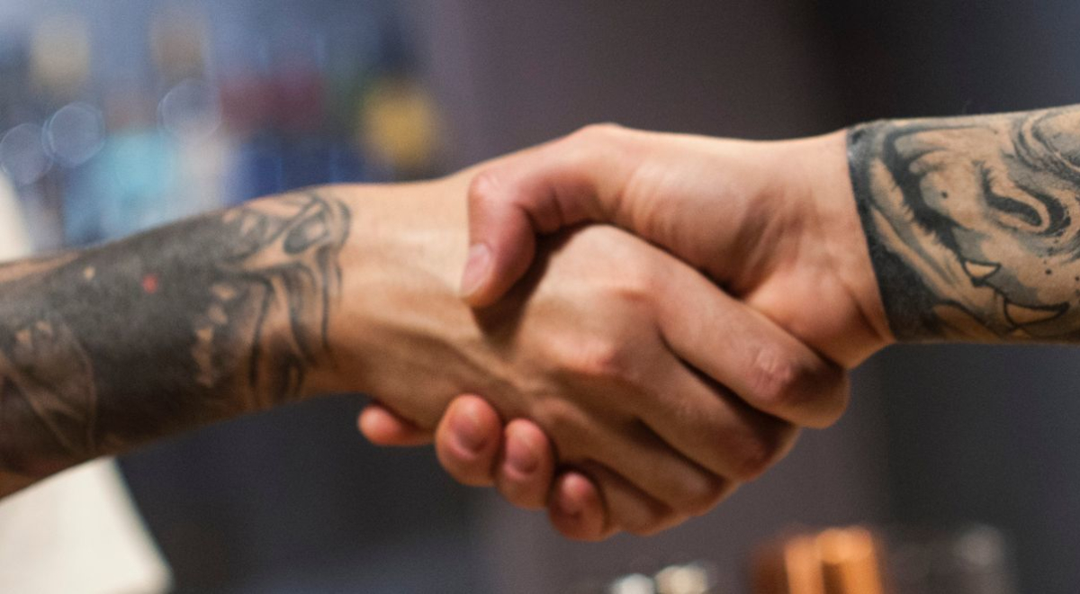Two tattooed arms shaking each other's hands