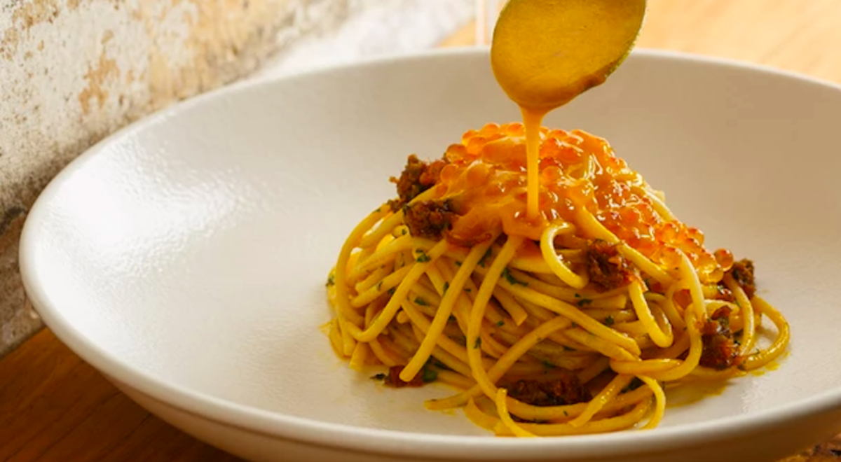 Source being poured onto a plate of pasta