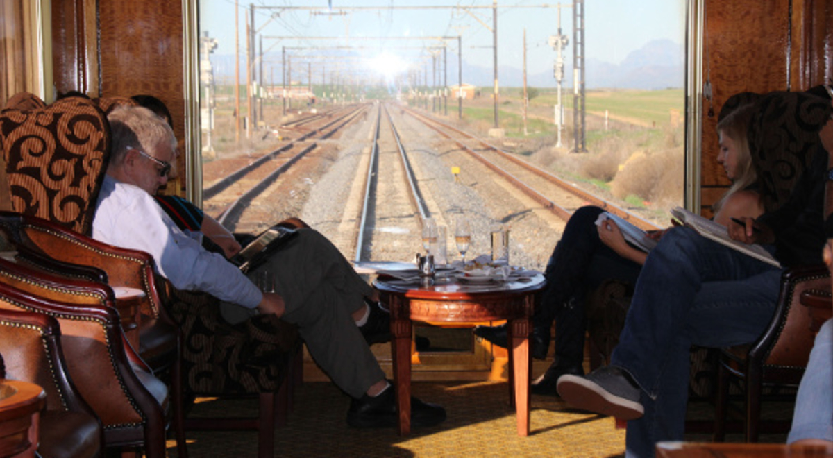 people riding the South Africa Blue Train enjoying its fancy interior with wooden tables and chairs