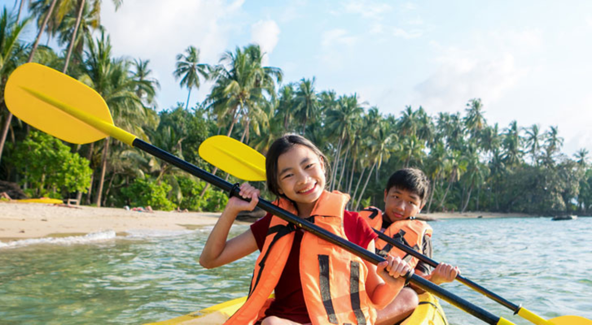 Two kids on a kayak with a yellow paddle stick