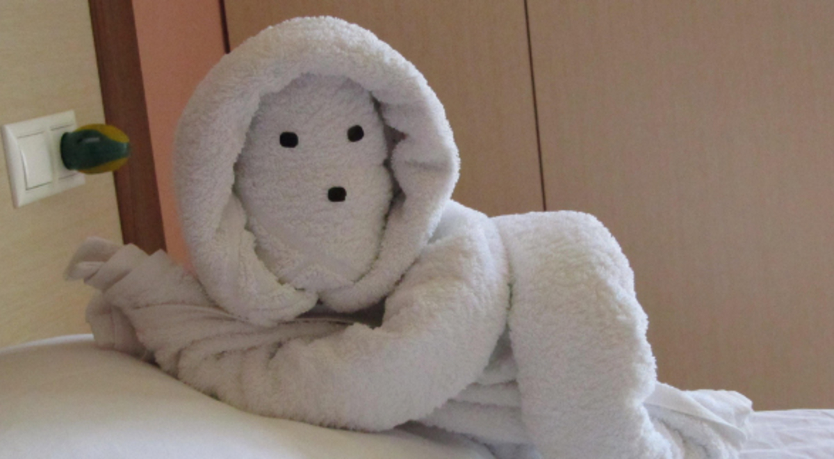 Towel origami in the shape of a person lying on the bed