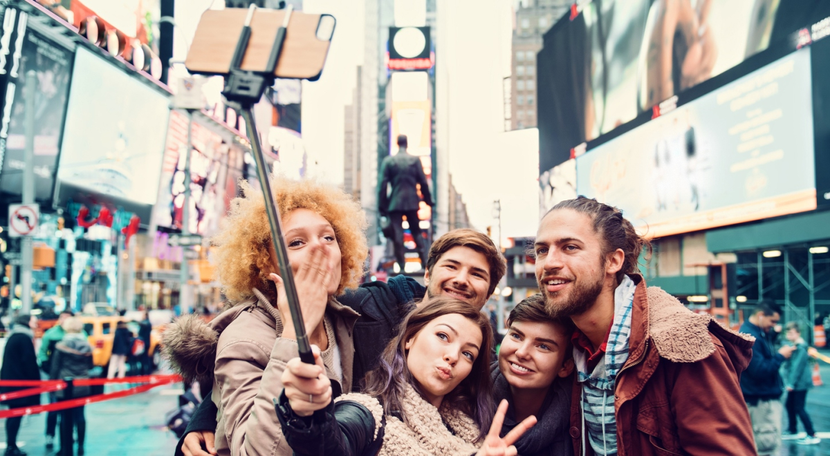 Group of five taking a photo in the city with a selfie stick